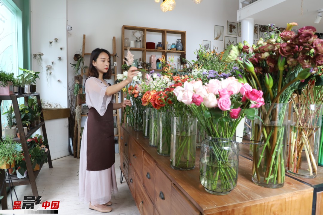 王黎媛是一名河南姑娘，在昆明念完大學(xué)后，就再也舍不下春城的藍天陽光、青山碧水，更舍不下這里的四時繁花，于是就干脆留了下來，成了一名媒體人。2017年的時候又毅然辭去工作，創(chuàng)業(yè)開起了花店，成了都市里的一名“花房姑娘”。圖為王黎媛在自己的花店中整理鮮花。新華網(wǎng) 周亞平/攝 念新洪/文